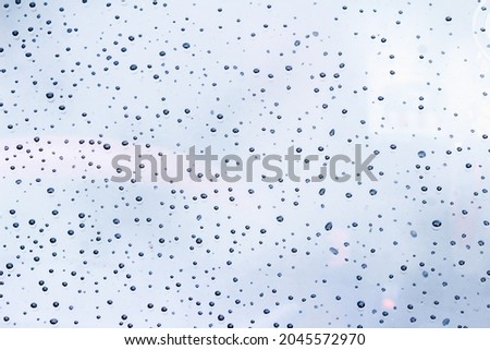 Blurred image of water droplets on the windshield of the car after the rainstorm has passed gives a feeling of loneliness. A large amount of raindrops settled on the windshield of the car.