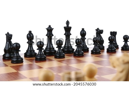 Set of black chess pieces on wooden board against white background
