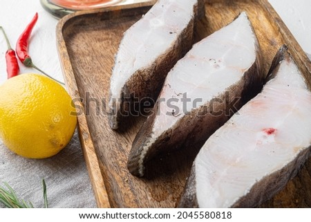Raw fish steak set, with ingredients and rosemary herbs, on white stone table background