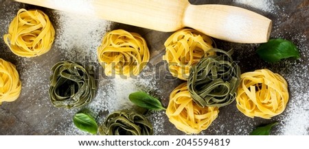 Raw pasta Tagliatelle Paglia e Fieno on a dark background. Selective focus. Space for text. Top view.