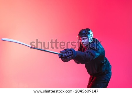 Championship preparation. Portrait of professional hockey player wearing special uniform training isolated over gradient pink background in neon. Concept of active life, team game, energy, sport, ad