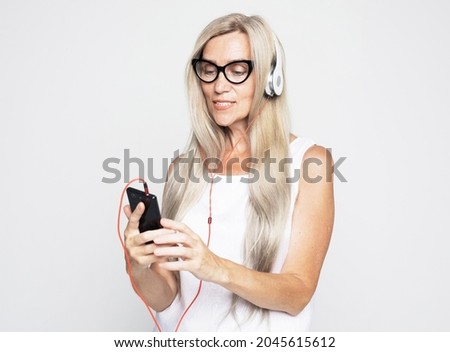 lifestyle, emotion and old people concept: Elderly woman with long white hair wearing white tshirt listening to music