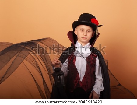 A boy with an American appearance in the costume of Count Dracula vampire And around flies a tulle with a place for the text concept of advertising discounts on Halloween shopping malls