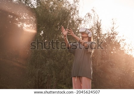 A girl wearing virtual reality glasses. He holds out his hands to the beam of sunlight. High quality photo