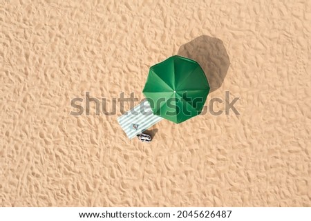Beach umbrella near towel and other vacationist's stuff on sand, aerial view Royalty-Free Stock Photo #2045626487