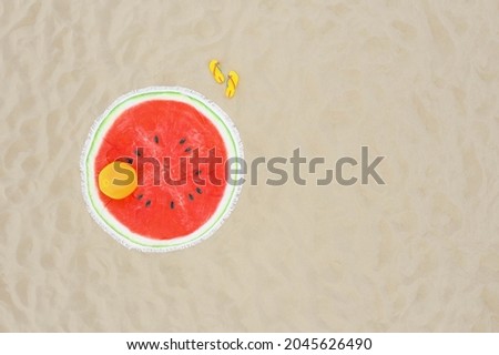 Round watermelon beach towel, ball and flip flops on sand, aerial view. Space for text