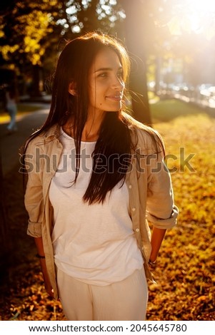 Outdoor atmospheric lifestyle photo of young beautiful lady at sunset. Brown hair and eyes. Warm autumn. Warm spring, the sun's rays from behind.