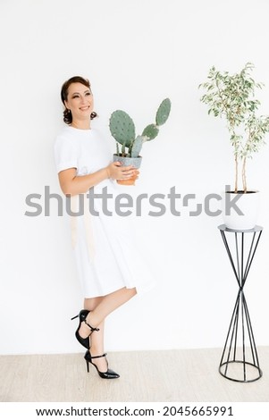 in the hands of a beautiful young girl, a large cactus in a clay pot on a white background.