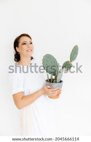 in the hands of a beautiful young girl, a large cactus in a clay pot on a white background.