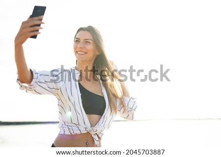 Happy young woman relaxing on the sandy beach. Beautiful woman taking selfie photo	