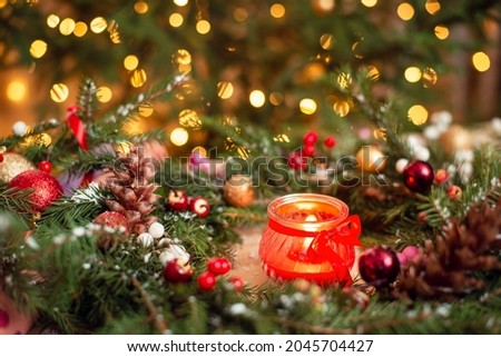 Close up shot of red burning candle in christmas wreath with bright colorful background. Festive Christmas mood