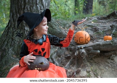 The witch admires her handmade bat. A girl dressed for Halloween is holding her pet, a rattle mouse, in her hand. Beautiful stylish picture for Halloween