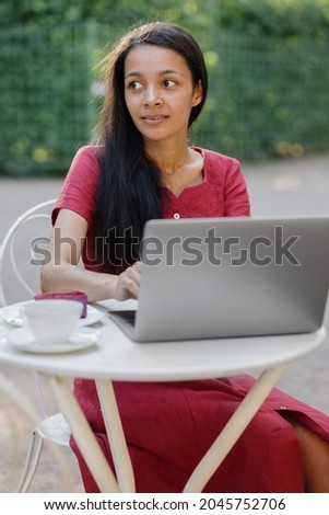 beautiful and young millennial african woman in a public place working on a laptop. african american businesswoman working in a park or doing online teaching. watching a webinar or creating content