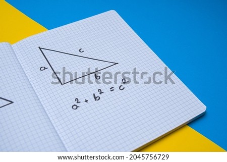 top view of a piece of paper with a drawn triangle and the Pythagorean theorem written on it. Concept showing the Pythagorean theorem on a colored background. A mathematical picture