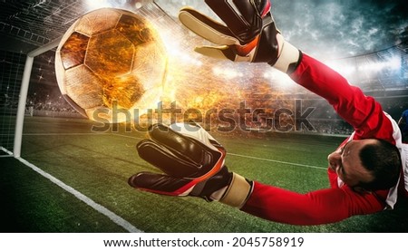 Close up of a soccer scene at night match with a goalkeeper trying to catch a fiery ball Royalty-Free Stock Photo #2045758919