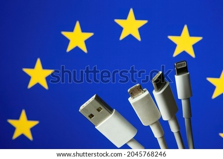 Concept for new EU legislation on USB-C universal charging cable. EUROPEAN UNION flag and different charging cables such as USB, USB-C, Micro USB, lightning cable.  Royalty-Free Stock Photo #2045768246