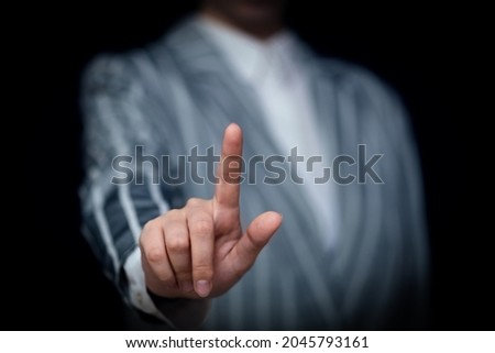 hand of a businesswoman with a raised forefinger, touch or press a button, screen, pick on a black background, free space, place for text, icons