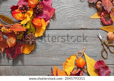 autumn leaves, scissors, ropes and fruits on a wooden table, decorate the house with autumn crafts for Thanksgiving, a wreath on the door of autumn leaves,