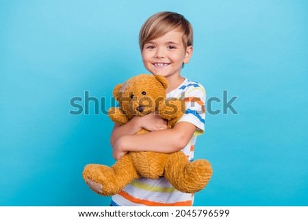 Photo of little relaxed calm boy enjoy cuddle teddy bear toy wear striped t-shirt isolated blue color background Royalty-Free Stock Photo #2045796599