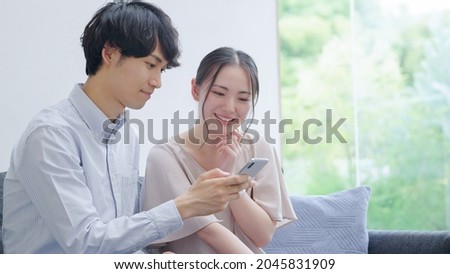 Asian young couple looking at a smartphone Royalty-Free Stock Photo #2045831909