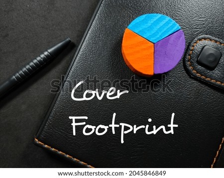 Text Cover Footprint writing on notebook with pen and colored block on a black background.
