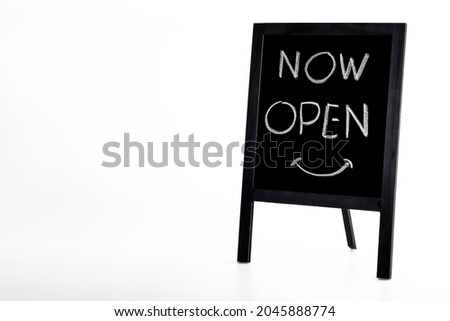 Hand writing 'Now Open' on small wooden vintage chalkboard on white background