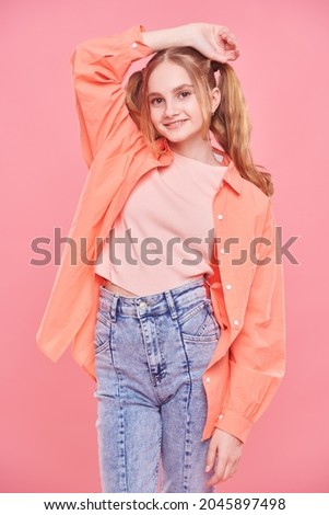Teenage style. Pretty teenage girl in bright summer clothes and with funny ponytails smiling at the camera. 