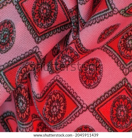 silk fabric of soft red color with a print of rhombuses, squares and medals. Tell a story and make a statement with traditional design work that has charm and value. Texture background pattern