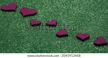 red hearts on a pale green background, focus on the third heart on the right
