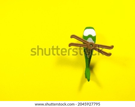 Green helicopter toy on a yellow background with copy space.