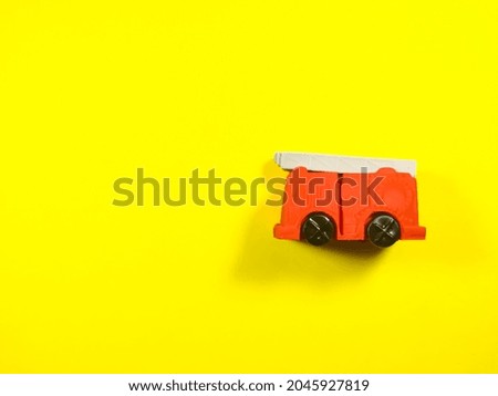 Red fire truck toy on a yellow background with copy space.