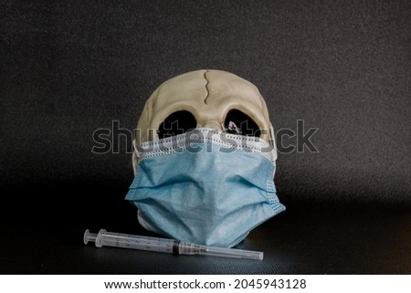 human skull wearing mask
COVID protection. deaths from coronavirus.
syringe beside