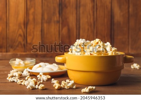 Bowls with tasty popcorn and butter on wooden background