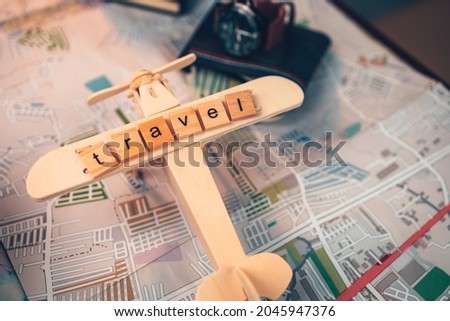 Wood square with word "travel" on airplan model, watch, money wallet, passport, camera on road map. Object for travel concept.