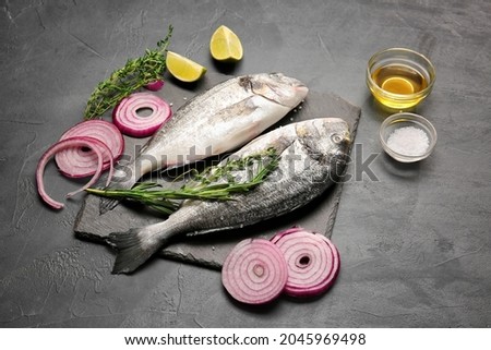 Raw dorado fish with ingredients on dark background