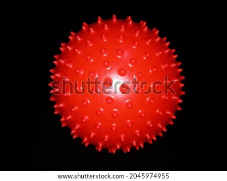 red spiked rubber ball black background.