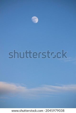 moon and clouds against blue sky