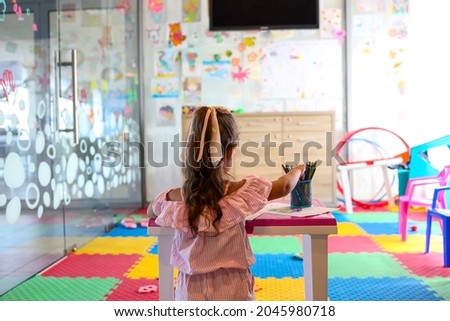Little girl drawing with color pen in paper on table at playroom, Baby healthy and preschool concept.