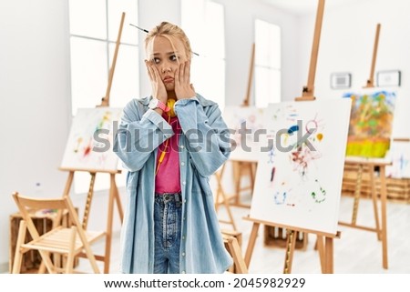 Young caucasian girl at art studio tired hands covering face, depression and sadness, upset and irritated for problem 