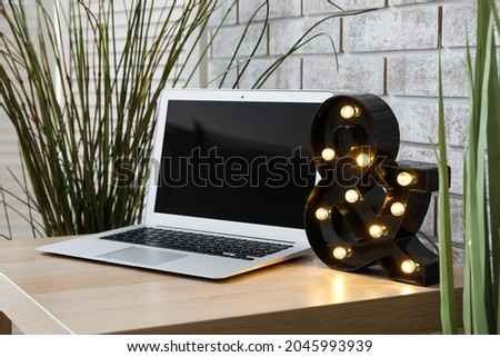Stylish decor and laptop on table near brick wall