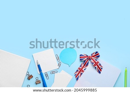 Stationery and ribbon in colors of UK flag on blue background. Concept of learning English