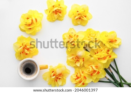 Cup of coffee and beautiful narcissus flowers on white background