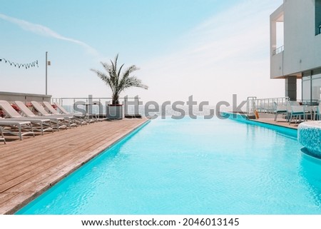 Summer outdoor swimming pool and sun loungers. In the hotel to rest. Seaview landscape. Royalty-Free Stock Photo #2046013145