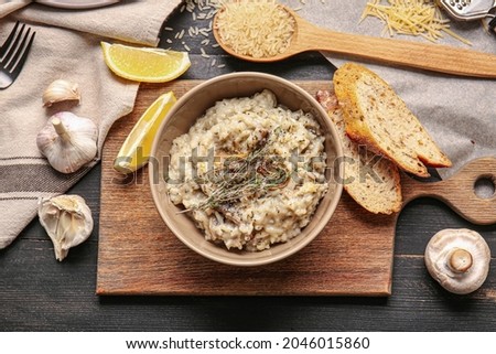 Bowl with tasty risotto on dark wooden background