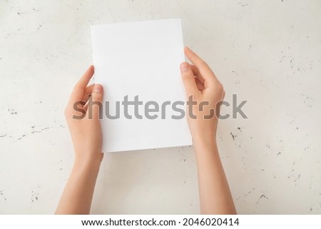 Female hands with blank paper on light background