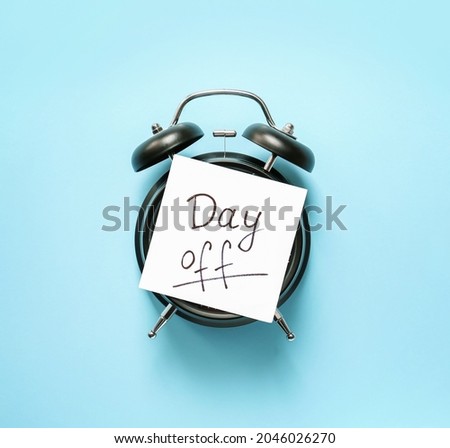 Alarm clock and paper sheet with text DAY OFF on color background Royalty-Free Stock Photo #2046026270