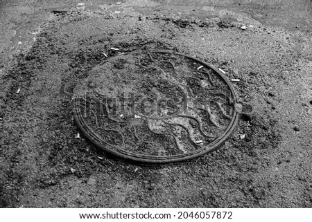 Black and white photo of a manhole on the road