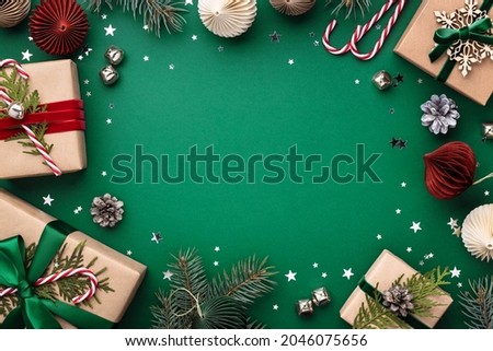 Christmas frame with gift boxes, holaday decorations and confetti on green background.