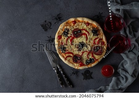 Halloween funny pizza with spiders, Creative idea for Halloween pizza on dark background with drinks and decorations, Copy space