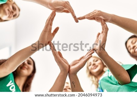 Group of young volunteers woman smiling happy make heart symbol with hands together at charity center. Royalty-Free Stock Photo #2046094973